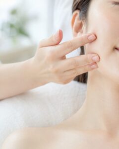 透明感のあるお客様の頬に、やさしく触れて肌を確認している手元。